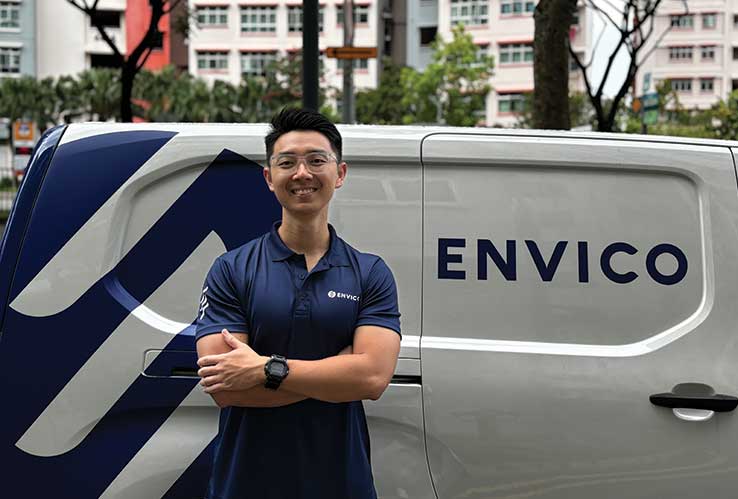 Envico professional cleaner standing confidently beside Envico service van in Singapore