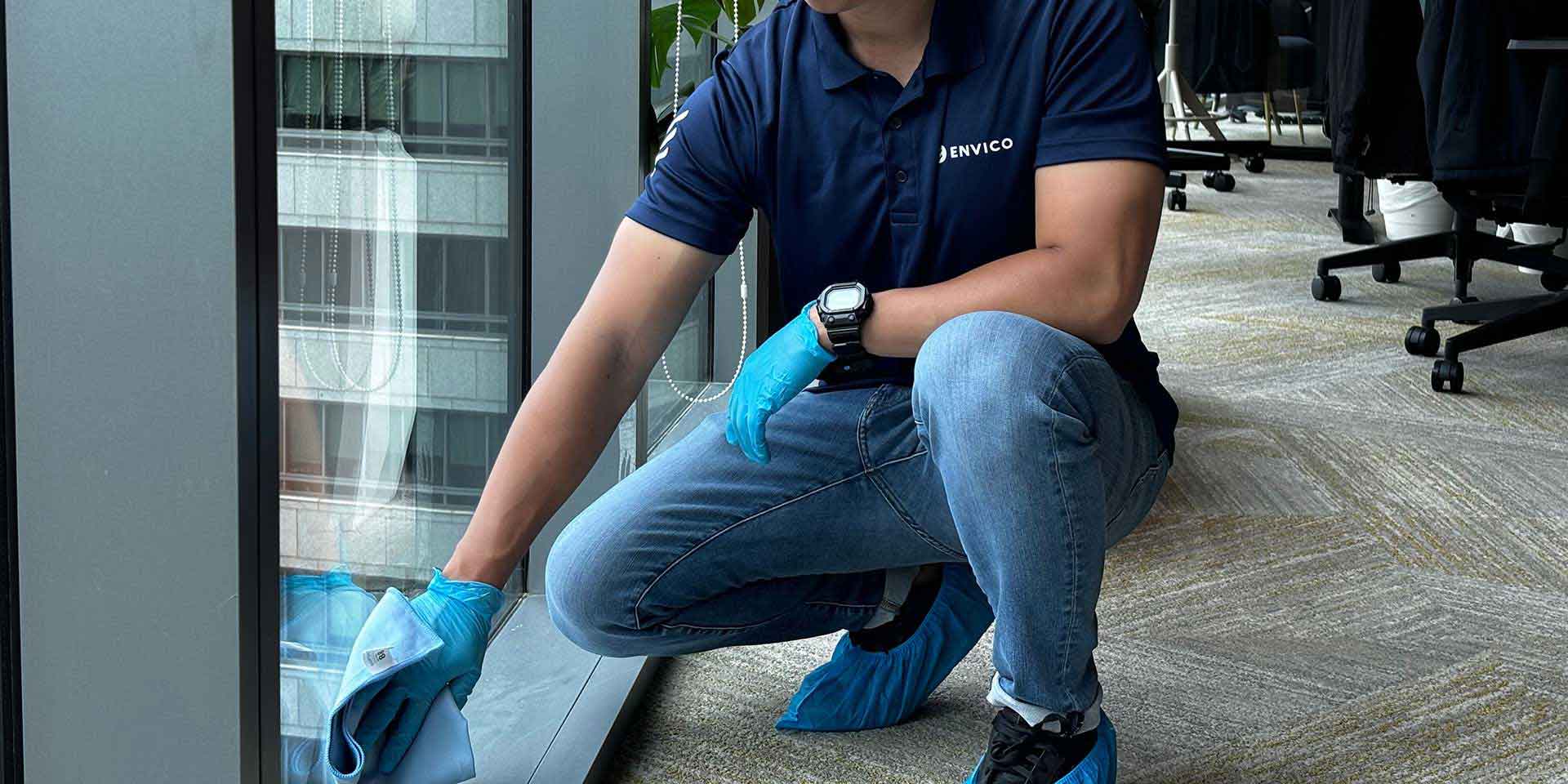 Envico professional cleaner wiping office window with gloves and protective gear in Singapore