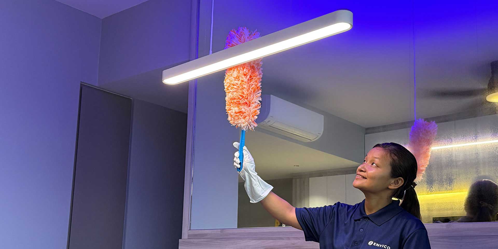 Envico cleaning specialist dusting ceiling light fixture during professional home cleaning service in Singapore