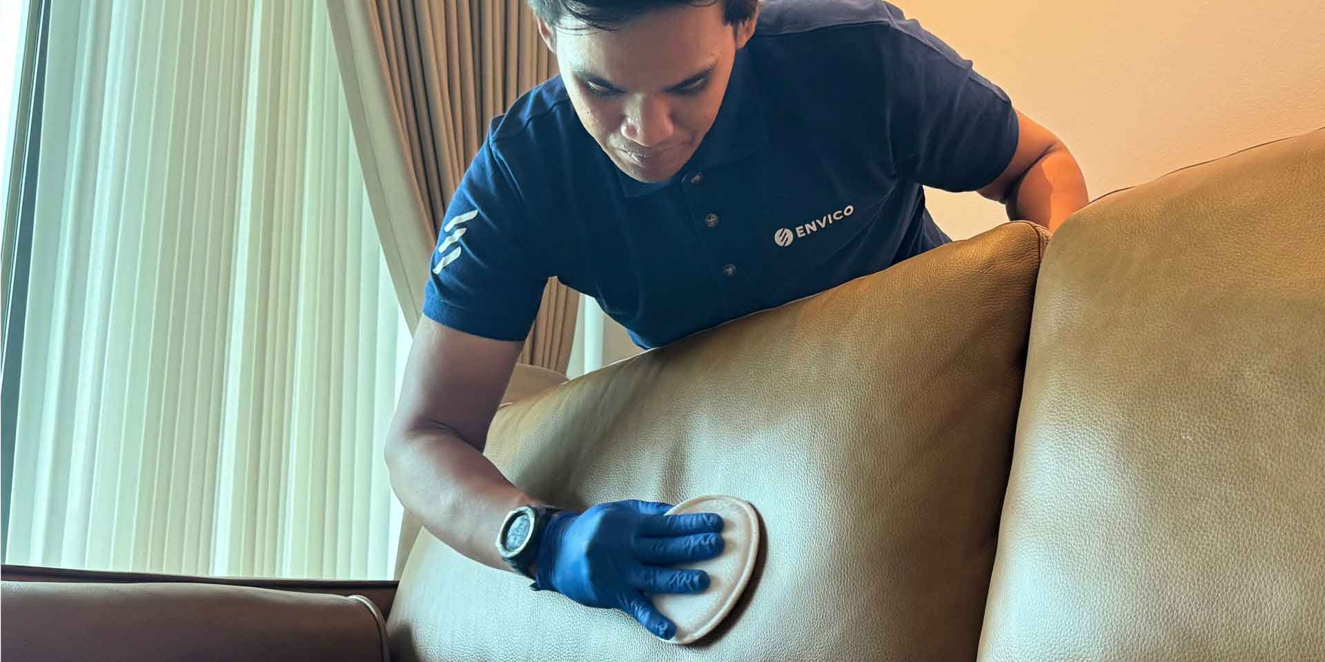 Envico professional cleaner performing leather sofa cleaning with protective gloves in Singapore